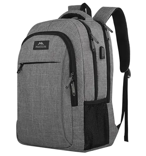 MATEIN grey anti-theft laptop backpack with USB charging port on a suitcase