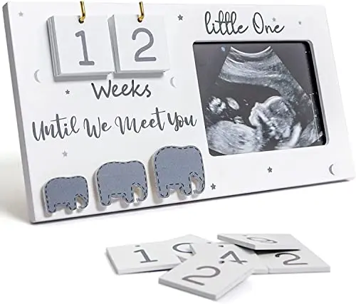 White wooden sonogram picture frame with slots for baby countdown numbers and a small elephant decoration.