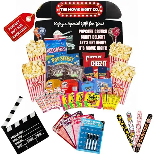 A colorful gift box overflowing with bags of popcorn, candy, chips, and fun movie night accessories like bingo cards and bracelets.