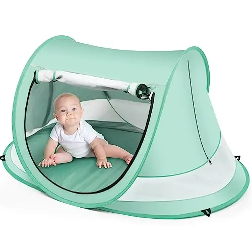 Green Kapeazo beach tent with mosquito netting deployed, secured with stakes on the sand.