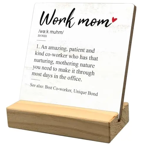 Small white wooden sign with 'Work Mom' definition text on a desk with a plant