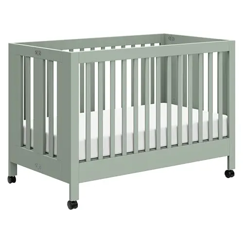 Babyletto Maki Portable Crib in light sage, folded with wheels for moving