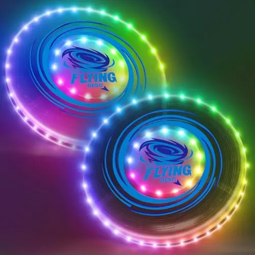 Two glowing LED flying discs lit up in the dark on a beach