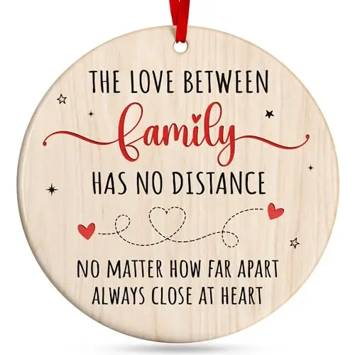 A set of festive, circular ceramic ornaments with modern family-themed designs, tied with red ribbons in a gift box.